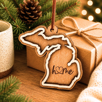Layered Michigan wood ornament with engraved “home” script and faux leather cord on white background.