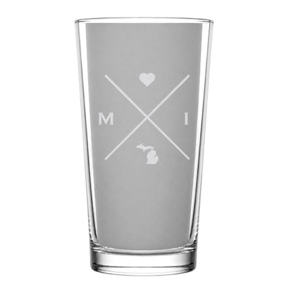 Clear pint glass with engraved Michigan crossed-line design, heart icon, and Michigan silhouette on a clean light background