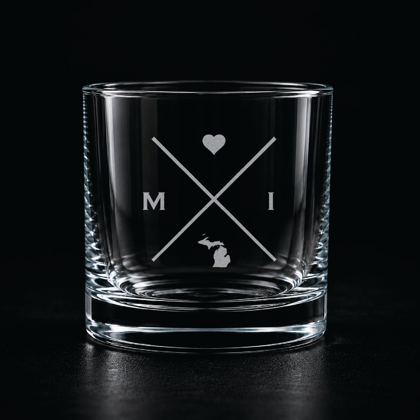 Engraved Michigan rocks glass with frosted Michigan silhouette and crossed-letter monogram on a dark background.