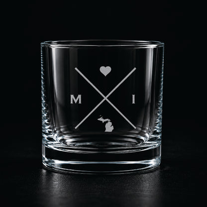 Engraved Michigan rocks glass with frosted Michigan silhouette and crossed-letter monogram on a dark background.