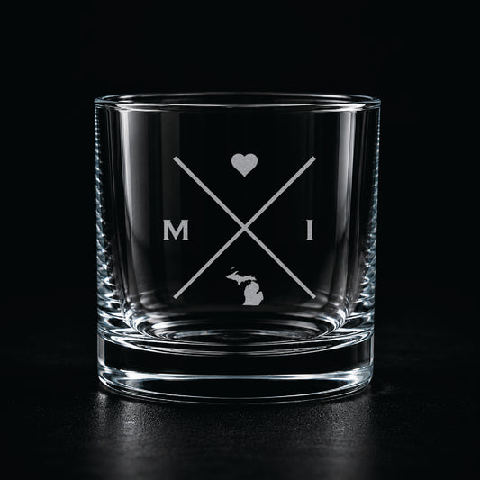 Engraved Michigan rocks glass with frosted Michigan silhouette and crossed-letter monogram on a dark background.