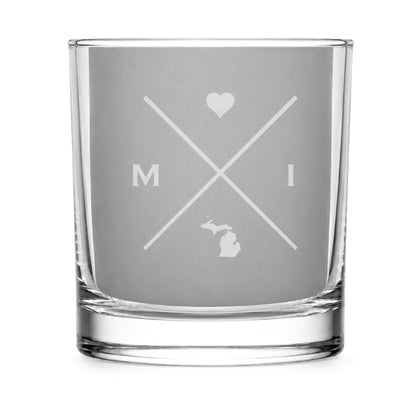 Clear engraved rocks glass featuring a minimalist crossed-line Michigan design with monogram initials, heart icon, and Michigan silhouette on a clean light background.