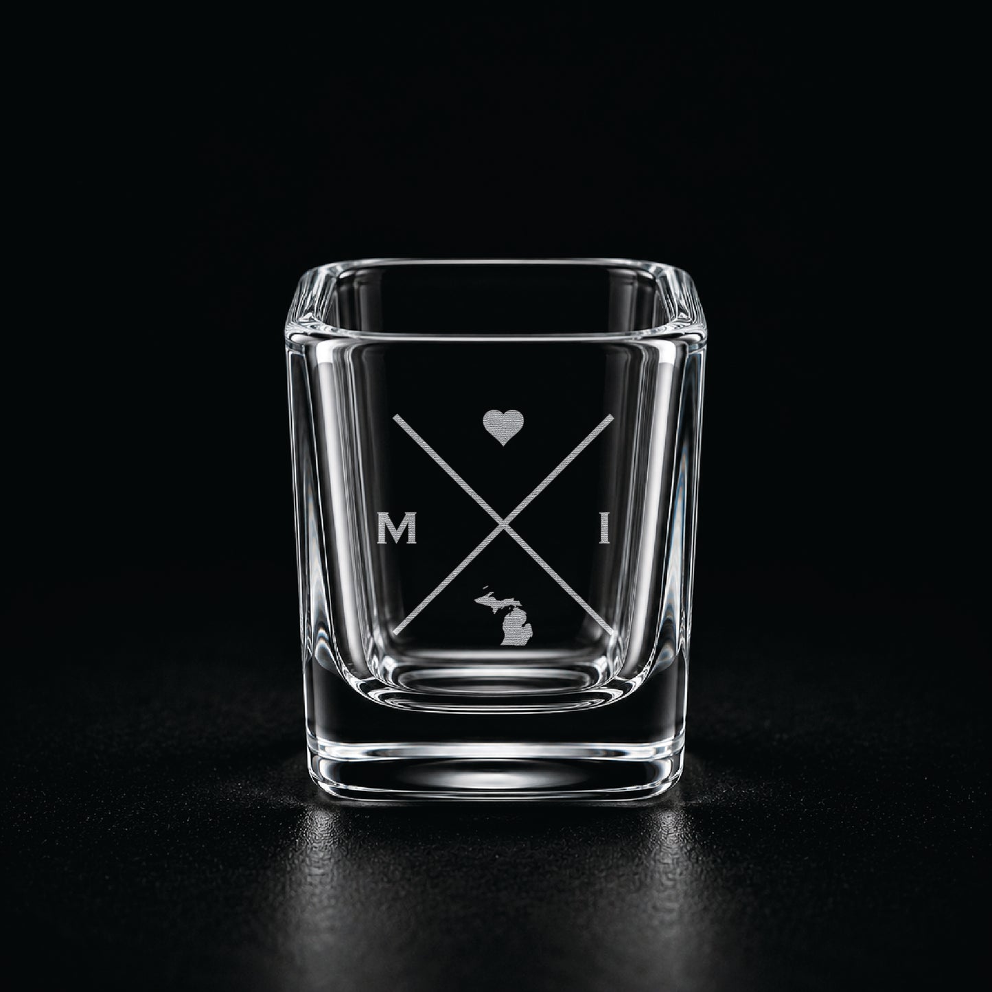 Engraved Michigan shot glass with modern crossed-line state design and frosted laser engraving on a dark background.