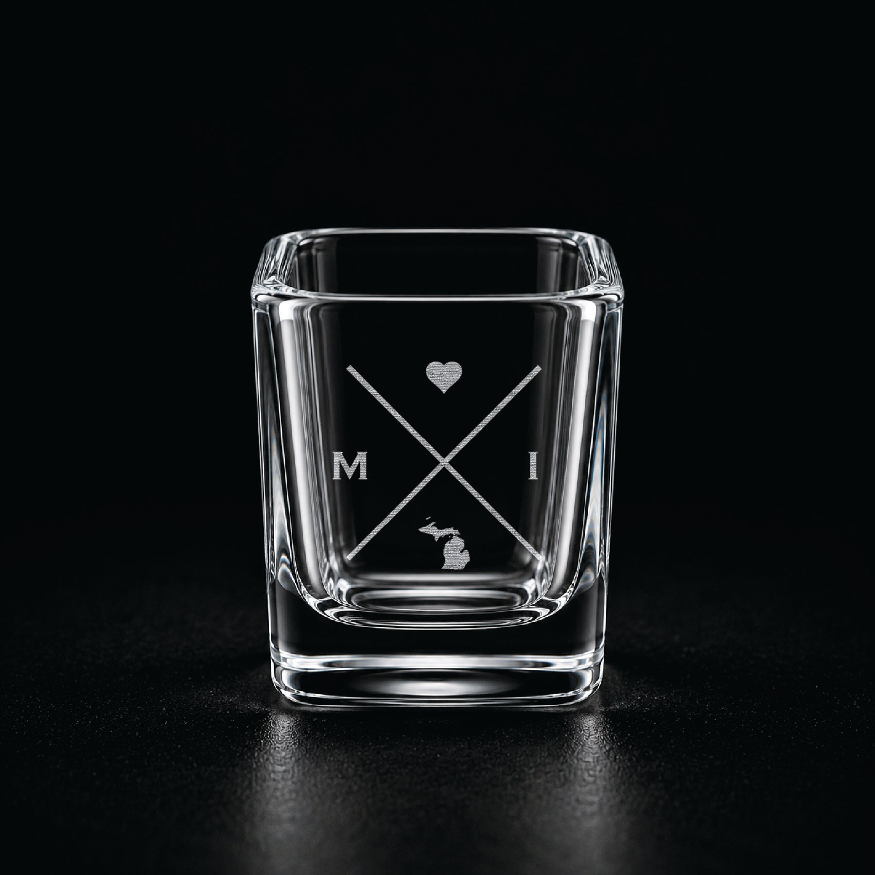 Engraved Michigan shot glass with modern crossed-line state design and frosted laser engraving on a dark background.