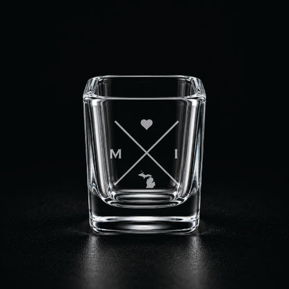 Engraved Michigan shot glass with modern crossed-line state design and frosted laser engraving on a dark background.