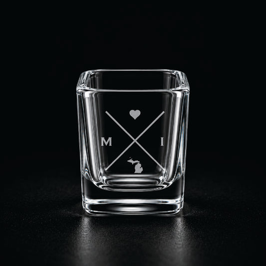Engraved Michigan shot glass with modern crossed-line state design and frosted laser engraving on a dark background.