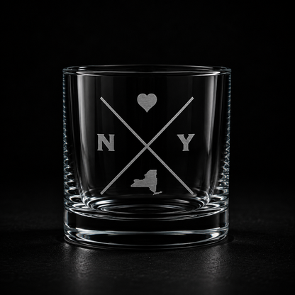 Engraved New York rocks glass with frosted New York silhouette and crossed-letter monogram on a dark background.