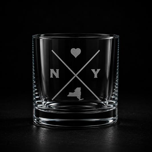 Engraved New York rocks glass with frosted New York silhouette and crossed-letter monogram on a dark background.