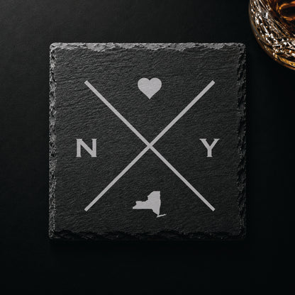 Dark slate coaster with engraved New York crossed-line design, heart icon, and New York silhouette on a dark background.