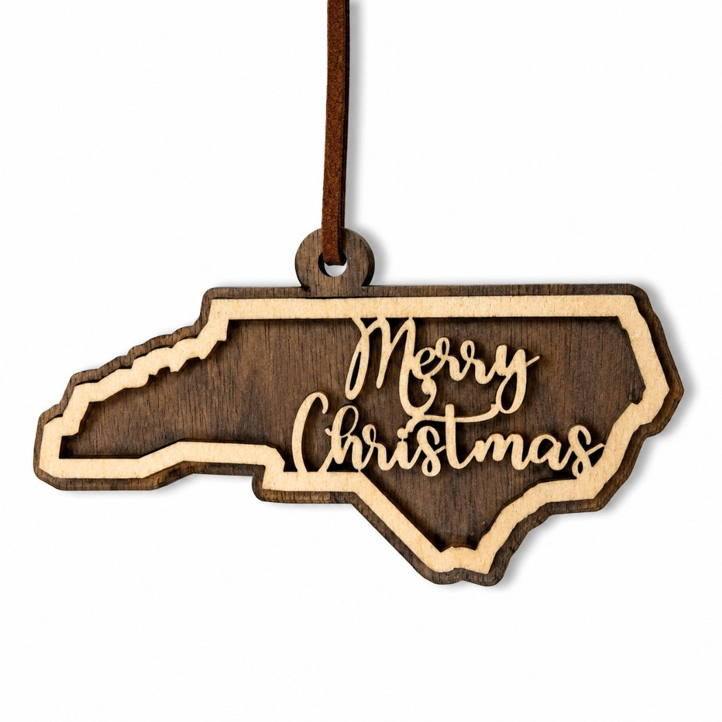 Wooden ornament shaped like North Carolina with 'Merry Christmas' text on a white background