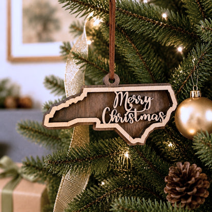 Wooden 'Merry Christmas' ornament shaped like North Carolina on a decorated Christmas tree.