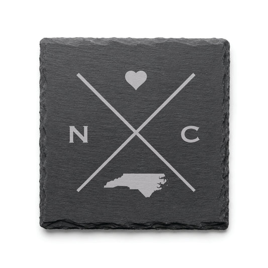 Engraved North Carolina slate coaster featuring a minimalist crossed-line design with heart detail and North Carolina silhouette on a clean light background.