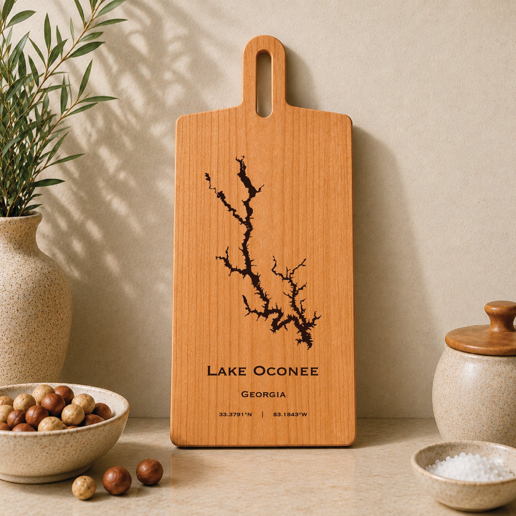 Lake Oconee engraved serving board displayed on a neutral kitchen countertop with ceramic decor