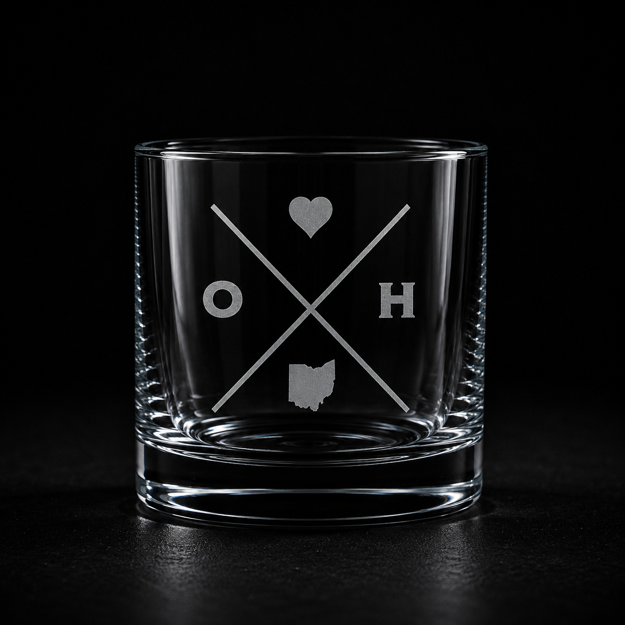Engraved Ohio rocks glass with frosted Ohio silhouette and crossed-letter monogram on a dark background.