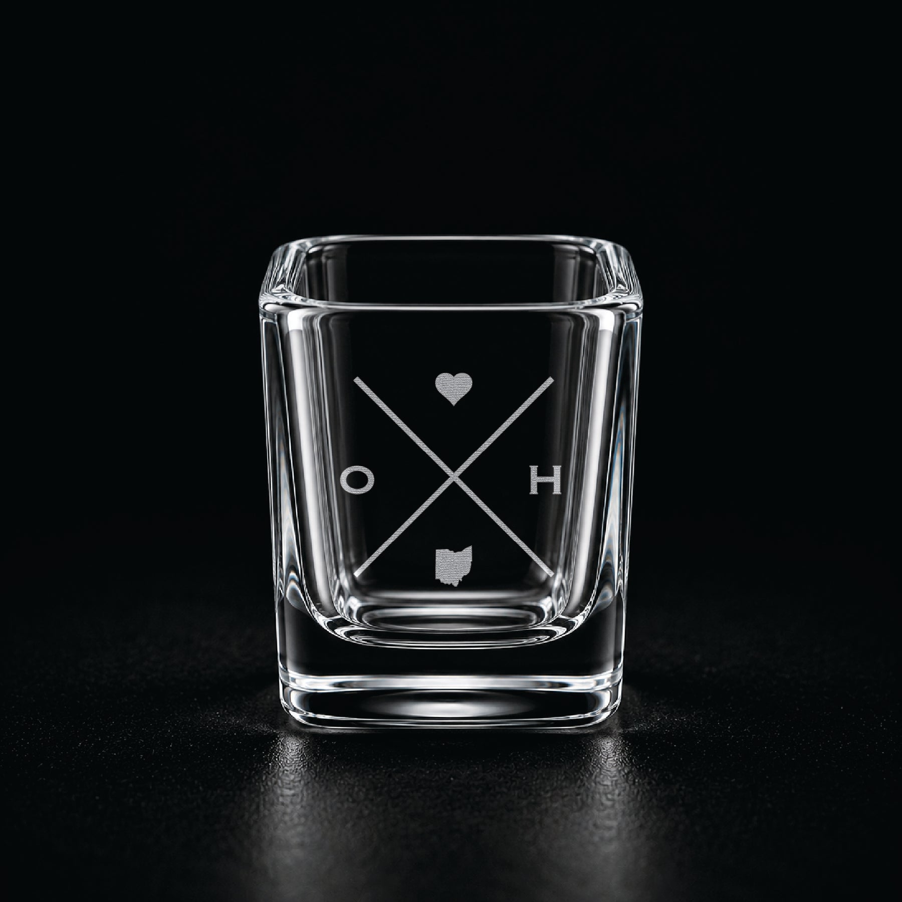 Engraved Ohio shot glass with modern crossed-line state design and frosted laser engraving on a dark background.