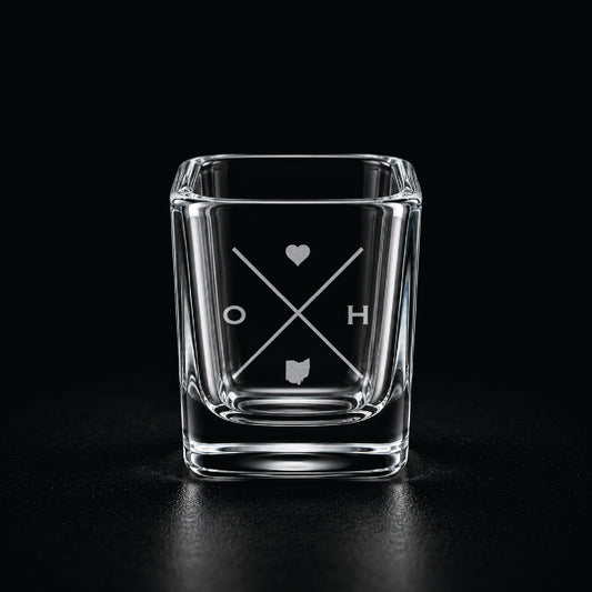 Engraved Ohio shot glass with modern crossed-line state design and frosted laser engraving on a dark background.