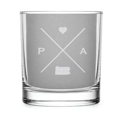 Clear engraved rocks glass featuring a minimalist crossed-line Pennsylvania design with monogram initials, heart icon, and Pennsylvania silhouette on a clean light background.