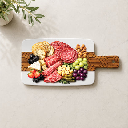 Marble and acacia serving board with engraved modern geometric pattern styled with cheese, cured meats, crackers, grapes, berries, and nuts.