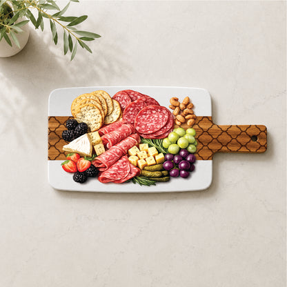 Marble and acacia charcuterie board with engraved quatrefoil pattern styled with cheese, cured meats, fruit, crackers, and nuts.