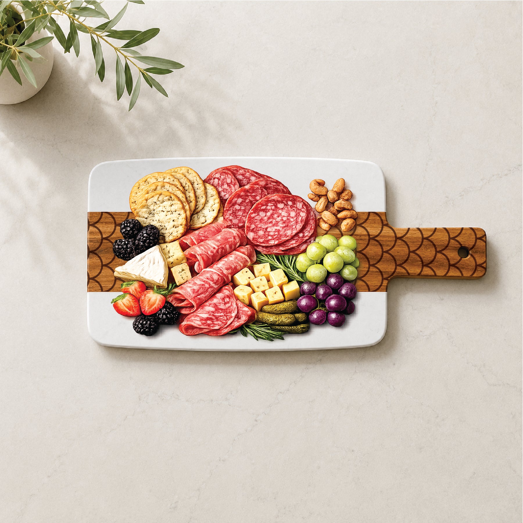 Marble and acacia charcuterie board with engraved scallop pattern styled with cheese, cured meats, fruit, crackers, and nuts.