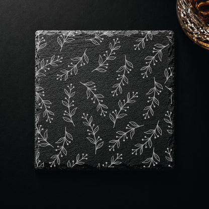 Floral Vine engraved slate coaster displayed beside a whiskey glass, showcasing an elegant botanical design engraved on natural slate.