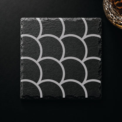 Scallop Pattern engraved slate coaster displayed on a dark tabletop beside a whiskey glass, showcasing a clean contemporary scallop design.