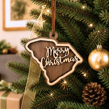Layered South Carolina state Christmas ornament hanging on a decorated holiday tree, featuring walnut and maple wood tones, “Merry Christmas” script, warm white lights, and neutral festive décor.