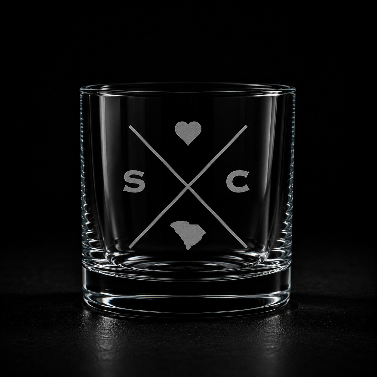 Engraved South Carolina rocks glass with frosted South Carolina silhouette and crossed-letter monogram on a dark background.