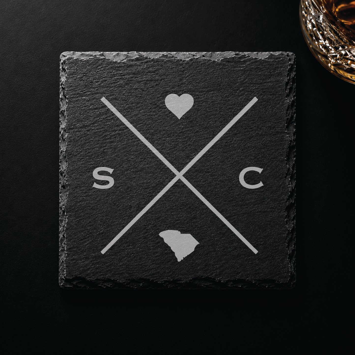 Dark slate coaster with engraved South Carolina crossed-line design, heart icon, and South Carolina silhouette on a dark background.