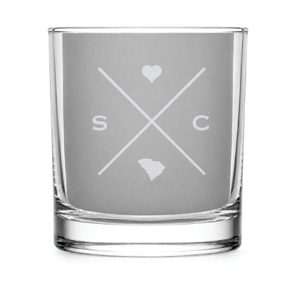 Clear engraved rocks glass featuring a minimalist crossed-line South Carolina design with monogram initials, heart icon, and South Carolina silhouette on a clean light background.