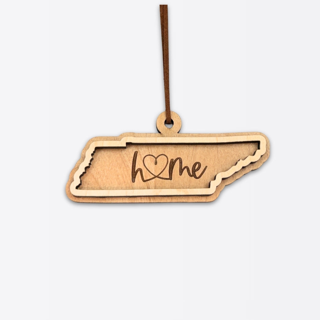 Layered Tennessee wood ornament with engraved “home” script and a faux leather cord on a white background.  