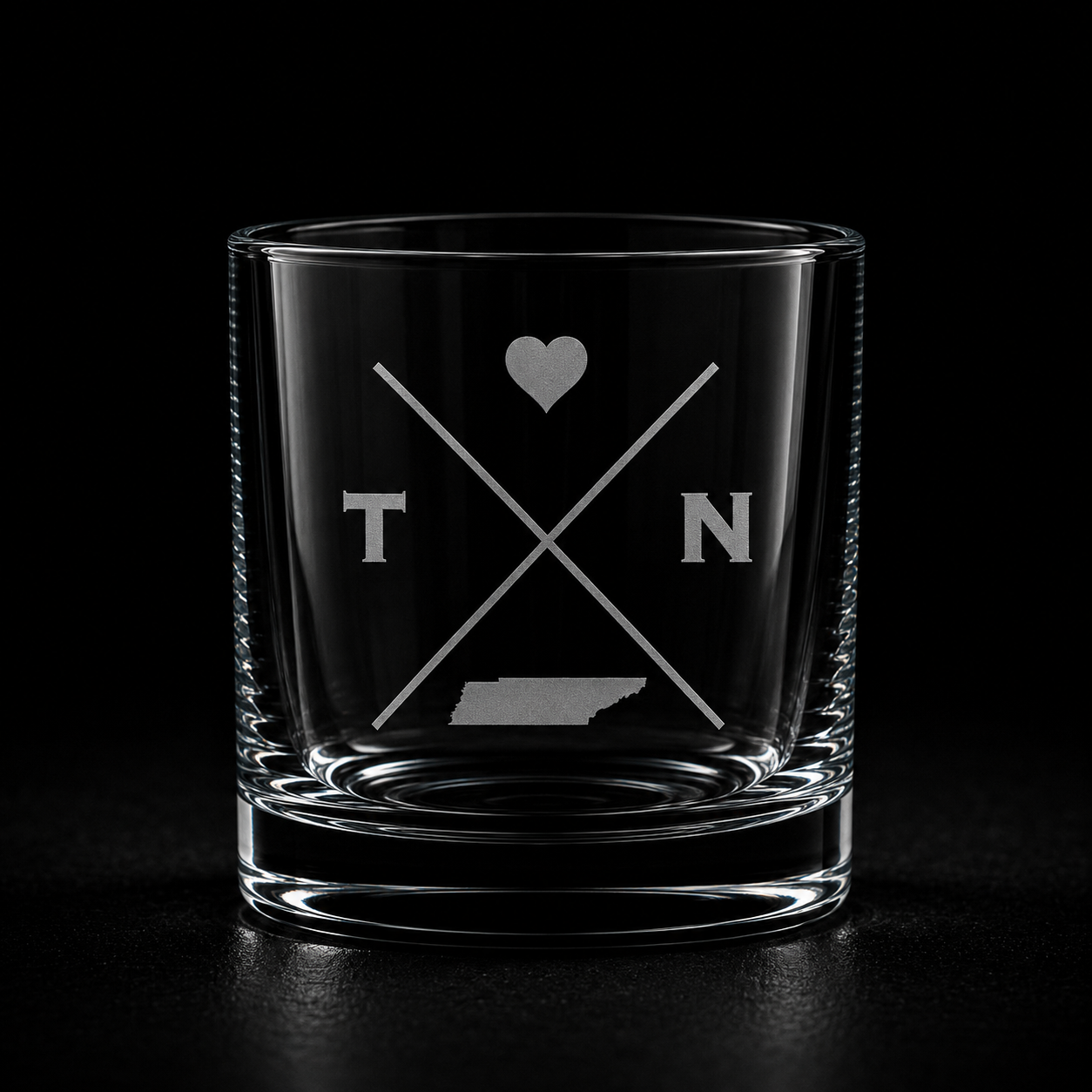 Engraved Tennessee rocks glass with frosted Tennessee silhouette and crossed-letter monogram on a dark background.