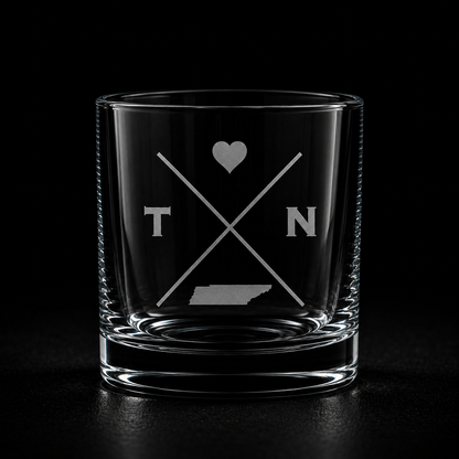 Engraved Tennessee rocks glass with frosted Tennessee silhouette and crossed-letter monogram on a dark background.