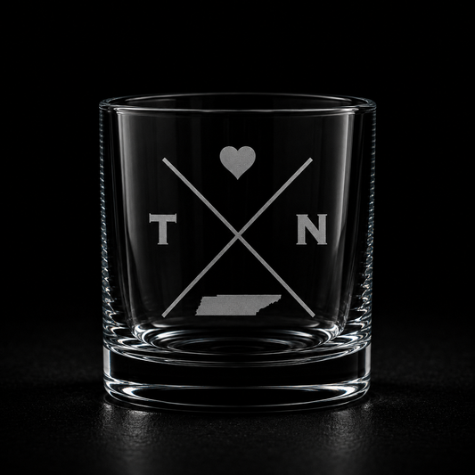 Engraved Tennessee rocks glass with frosted Tennessee silhouette and crossed-letter monogram on a dark background.