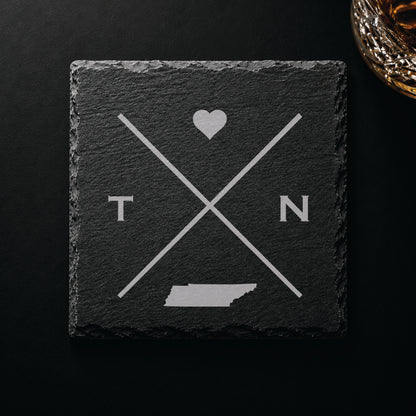 Dark slate coaster with engraved Tennessee crossed-line design, heart icon, and Tennessee silhouette on a dark background.