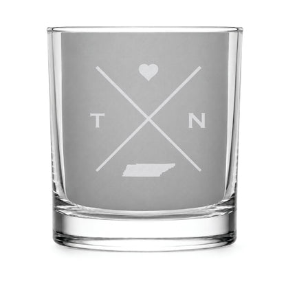 Clear engraved rocks glass featuring a minimalist crossed-line Tennessee design with monogram initials, heart icon, and Tennessee silhouette on a clean light background.