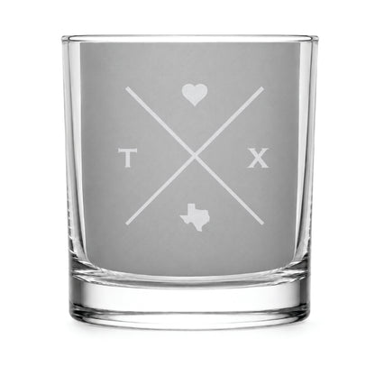 Clear engraved rocks glass featuring a minimalist crossed-line Texas design with monogram initials, heart icon, and Texas silhouette on a clean light background.
