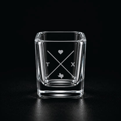 Engraved Texas shot glass with modern crossed-line state design and frosted laser engraving on a dark background.
