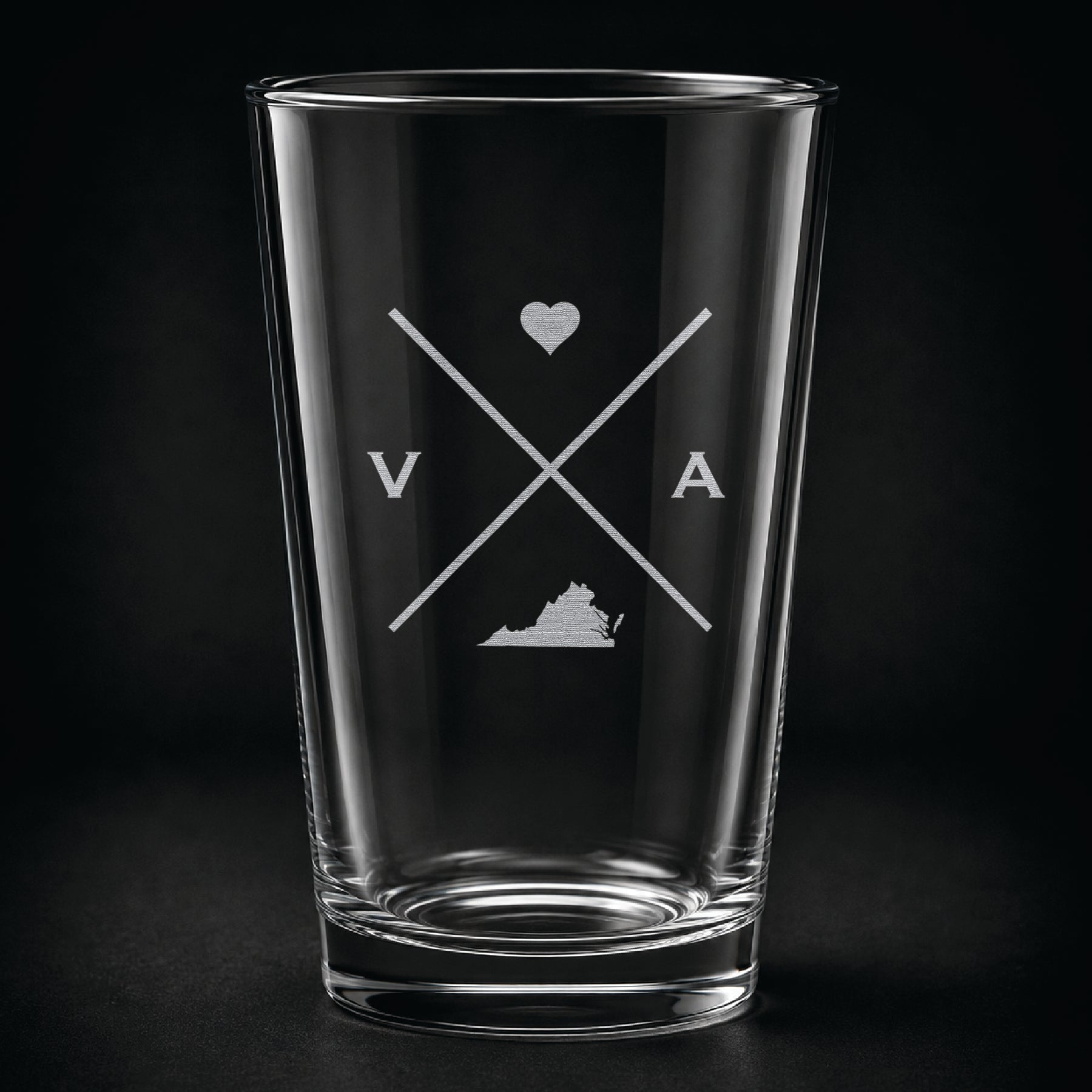 Engraved Virginia pint glass featuring a minimalist crossed-line design with heart detail and Virginia silhouette on a dark background.