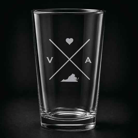 Engraved Virginia pint glass featuring a minimalist crossed-line design with heart detail and Virginia silhouette on a dark background.