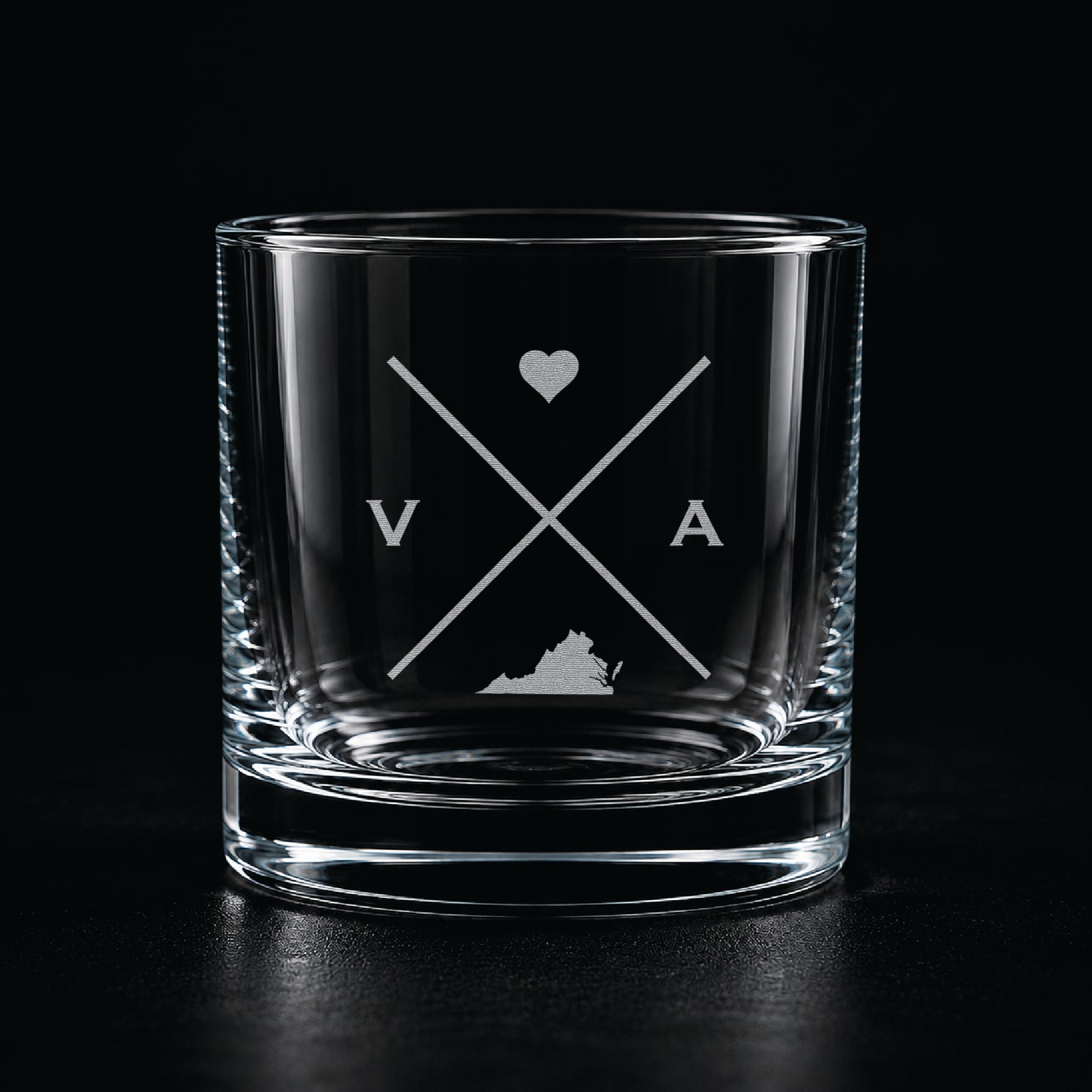 Engraved Virginia rocks glass with frosted Virginia silhouette and crossed-letter monogram on a dark background.
