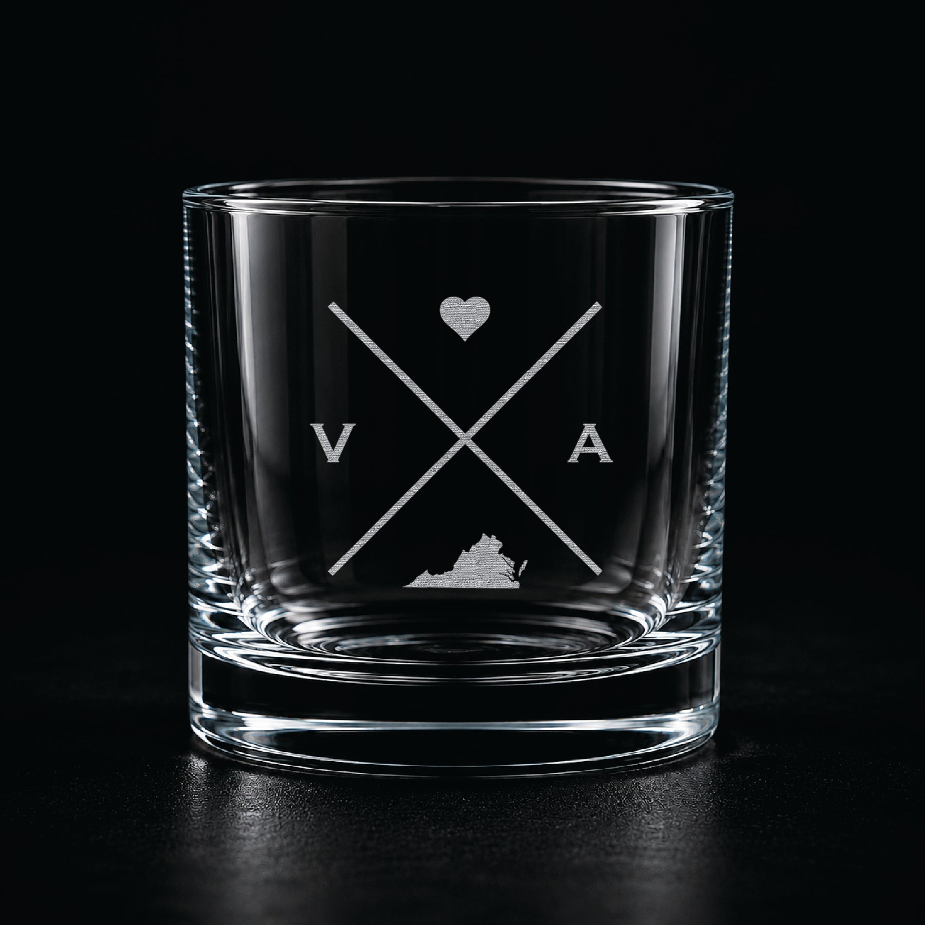 Engraved Virginia rocks glass with frosted Virginia silhouette and crossed-letter monogram on a dark background.