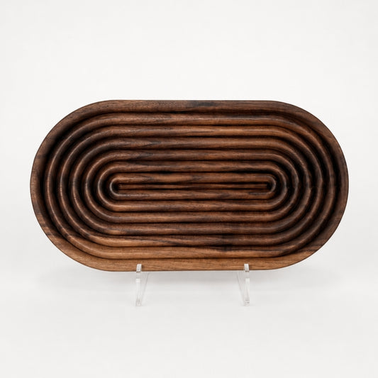 Walnut wood bread board on white background with fluted carved detailing, rounded raised ridges, and warm cherry wood grain displayed on a clear acrylic stand.