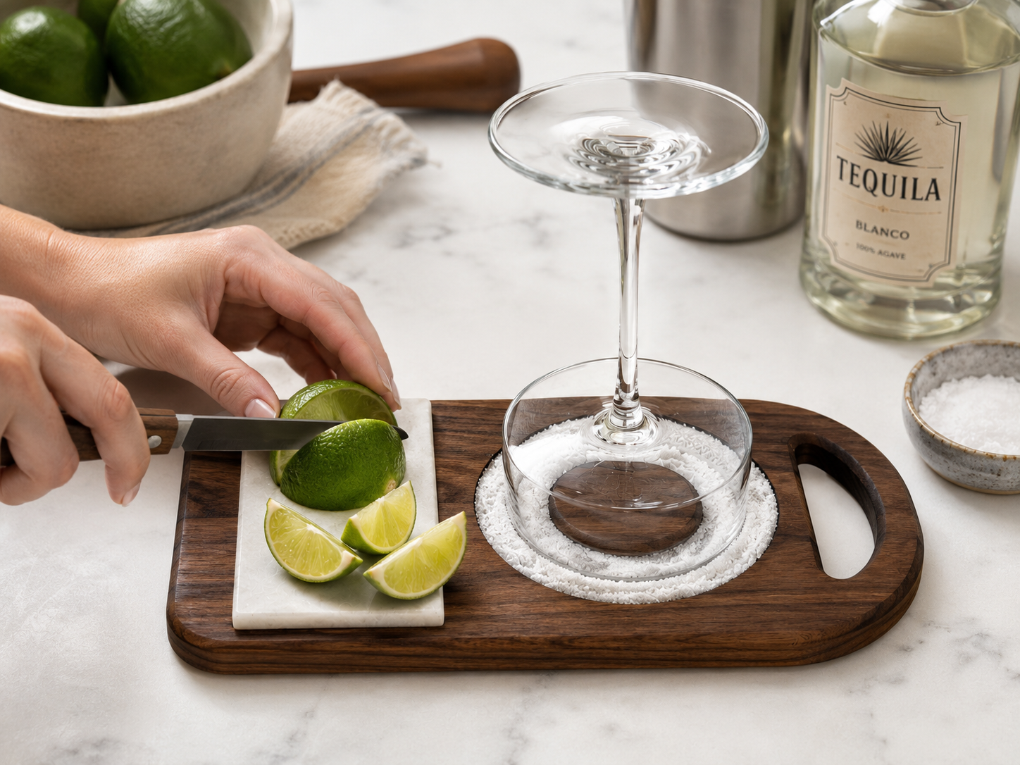 In-use photo of walnut wood margarita rimmer with lime being sliced on removable marble tile beside prepared margarita glass.