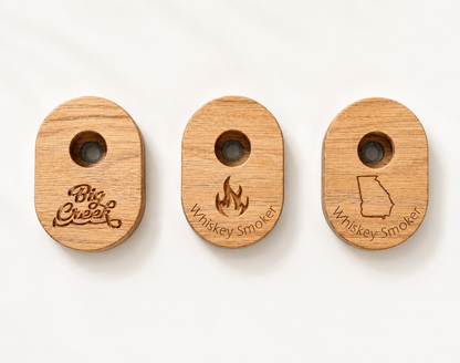 Three wooden whiskey smokers displayed side by side showing design options: custom logo, flame design, and Georgia state outline.