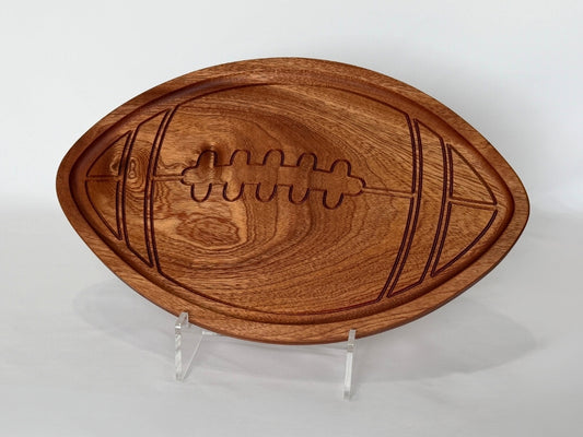Football-shaped wooden serving tray with a fully recessed center and carved rim detail, displayed on a white background with visible wood grain and engraved football stitching design.