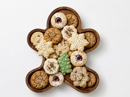 Gingerbread-shaped wooden tray filled with assorted holiday cookies, arranged edge-to-edge within the recessed center, shown on a clean white background.