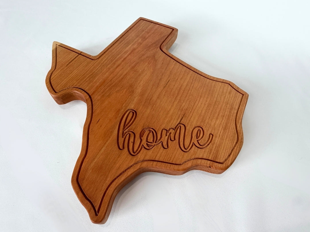 Texas shaped hardwood serving board with engraved “home” detail on clean white background