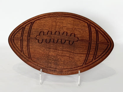 Football-shaped wooden charcuterie board with engraved laces, styled flat on a clean white background.