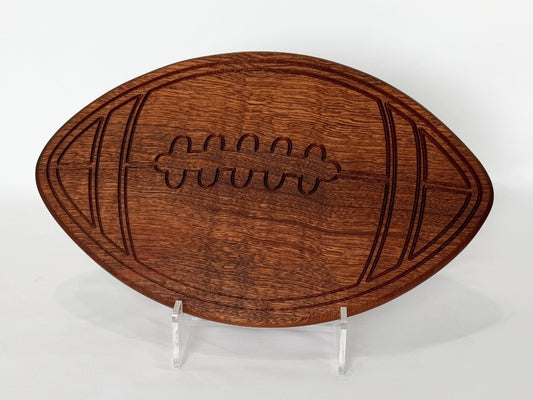 Football-shaped wooden charcuterie board with engraved laces, styled flat on a clean white background.